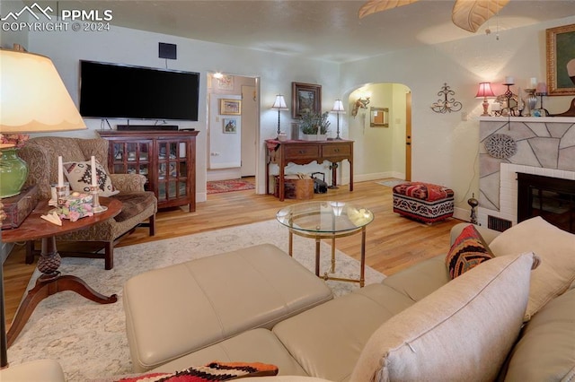 living room with a brick fireplace and hardwood / wood-style flooring