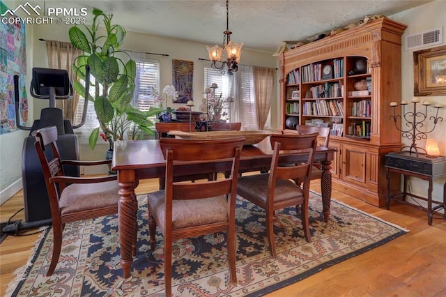 dining area featuring an inviting chandelier, light wood-type flooring, and a textured ceiling