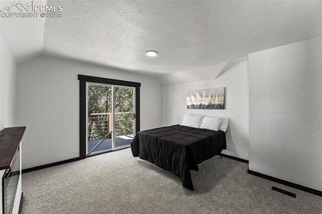 carpeted bedroom with a textured ceiling, lofted ceiling, and access to exterior