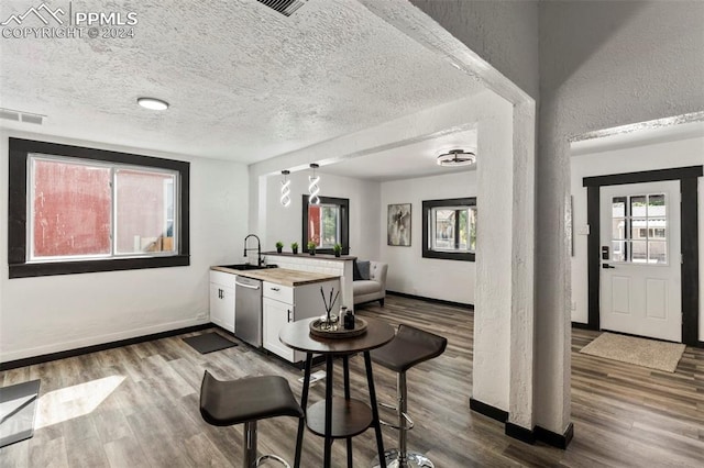 interior space with white cabinets, sink, wooden counters, dishwasher, and hardwood / wood-style flooring