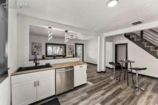 kitchen featuring wooden counters, stainless steel dishwasher, decorative light fixtures, white cabinetry, and dark hardwood / wood-style floors