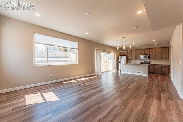 unfurnished living room with wood-type flooring, a notable chandelier, and sink