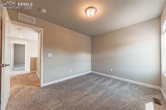 carpeted empty room featuring a textured ceiling