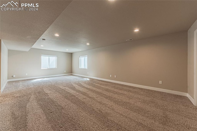 empty room with carpet floors and a textured ceiling