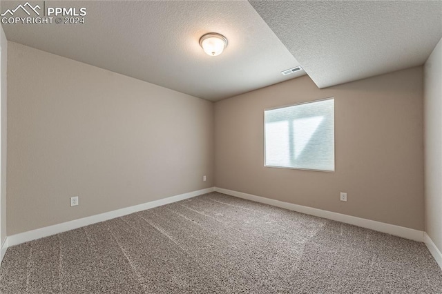 carpeted empty room featuring a textured ceiling