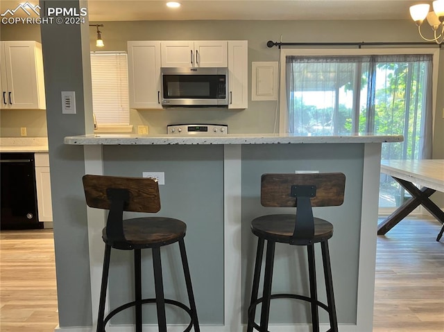 kitchen with white cabinets, light hardwood / wood-style floors, and a kitchen bar