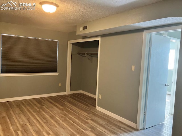 unfurnished bedroom with hardwood / wood-style floors, a textured ceiling, and a closet