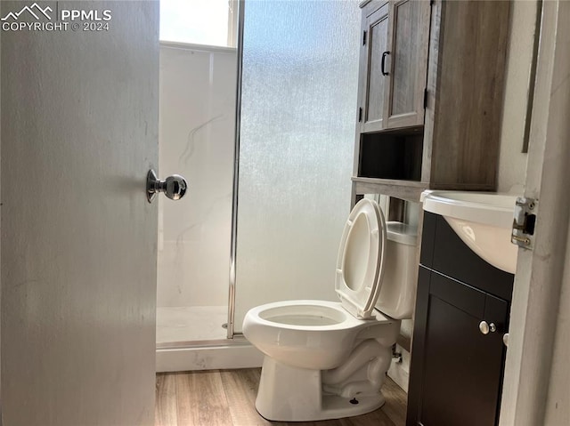 bathroom featuring hardwood / wood-style floors, vanity, toilet, and a shower with door