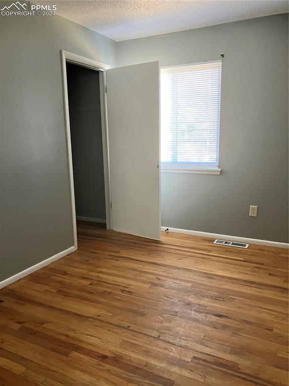 unfurnished bedroom with a closet, a textured ceiling, and hardwood / wood-style flooring