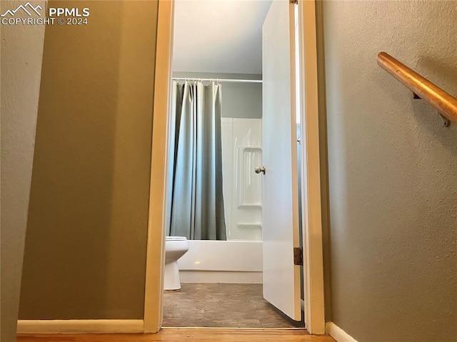 bathroom featuring hardwood / wood-style flooring, toilet, and shower / tub combo with curtain