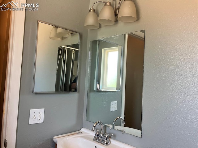 bathroom featuring walk in shower, a notable chandelier, and sink