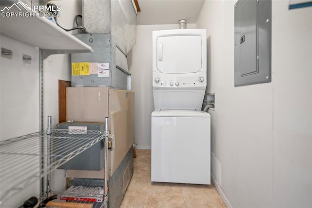 laundry room featuring electric panel and stacked washer / drying machine