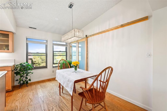 dining room with light wood-type flooring and a textured ceiling