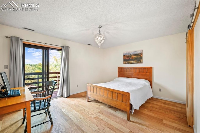 bedroom featuring light wood-type flooring, a chandelier, a textured ceiling, and access to exterior