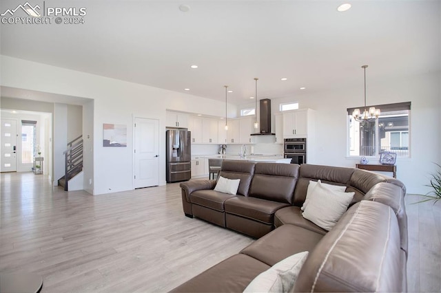 living room with a notable chandelier, sink, and light hardwood / wood-style floors