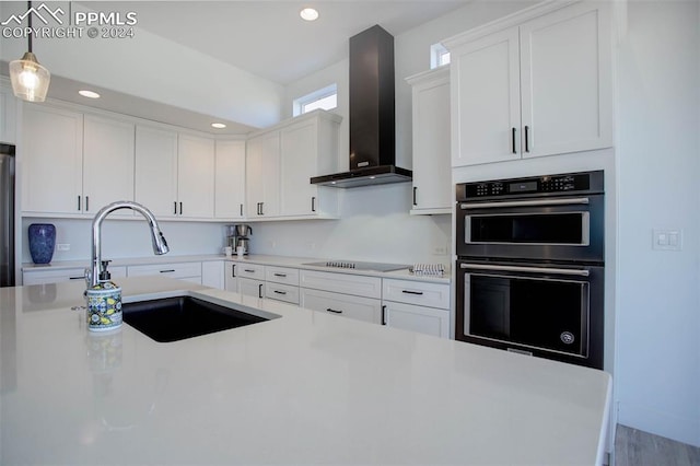 kitchen featuring black electric stovetop, sink, white cabinetry, stainless steel double oven, and wall chimney exhaust hood