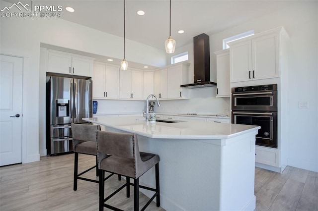 kitchen featuring wall chimney exhaust hood, white cabinetry, appliances with stainless steel finishes, and sink