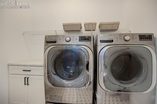 laundry room featuring washer and clothes dryer and cabinets