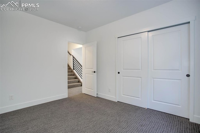 unfurnished bedroom with dark colored carpet and a closet