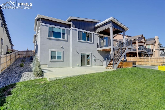 rear view of property featuring a lawn, a wooden deck, and a patio area