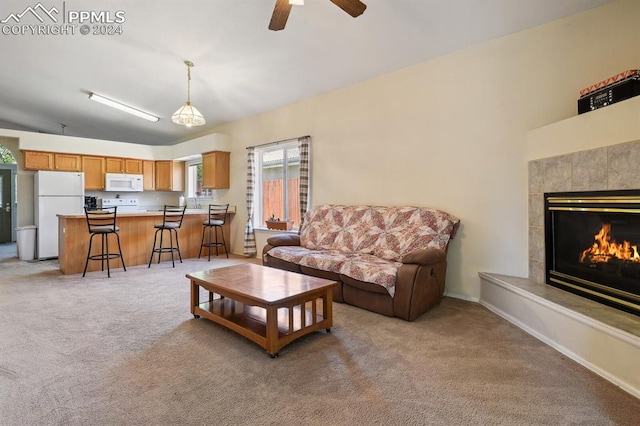 living room with a tile fireplace, ceiling fan, light colored carpet, and vaulted ceiling