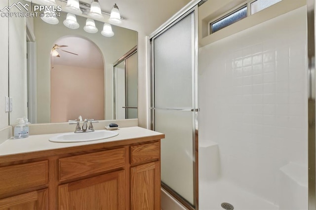 bathroom with walk in shower, vanity, and ceiling fan