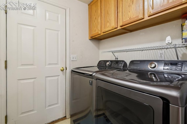 clothes washing area featuring cabinets and washer and dryer