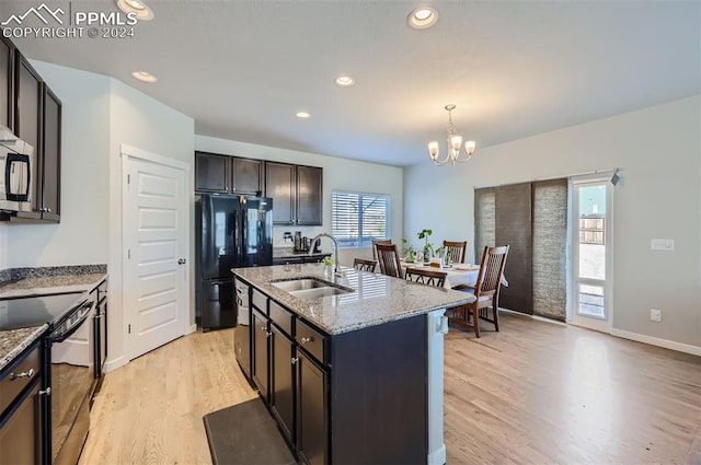 kitchen with a wealth of natural light, black appliances, a center island with sink, and sink