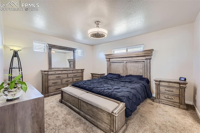 bedroom featuring light carpet, multiple windows, and a textured ceiling