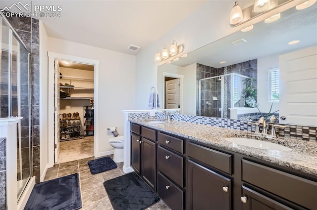 bathroom featuring backsplash, vanity, an enclosed shower, toilet, and tile patterned floors