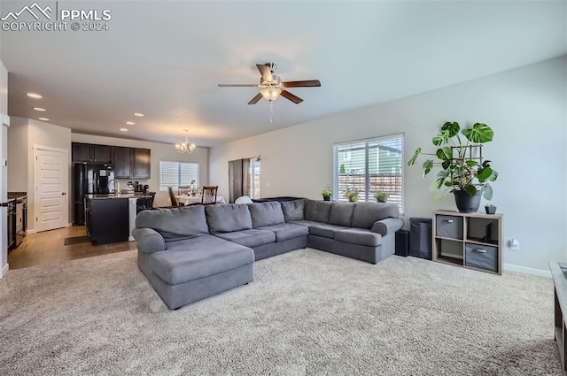 carpeted living room with ceiling fan with notable chandelier