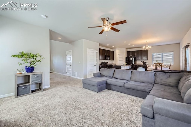 carpeted living room featuring ceiling fan with notable chandelier