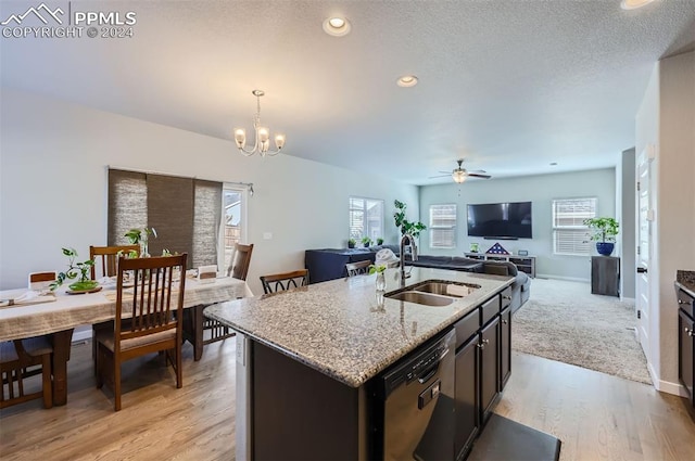 kitchen with an island with sink, sink, decorative light fixtures, dishwasher, and ceiling fan with notable chandelier