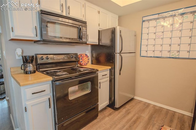 kitchen featuring electric range, stainless steel refrigerator, light wood-type flooring, and white cabinetry