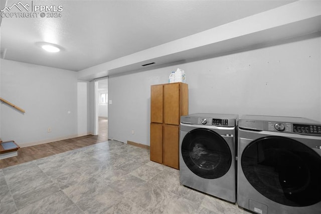 laundry room featuring cabinets, light wood-type flooring, and washing machine and dryer