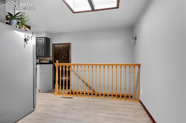 corridor featuring light hardwood / wood-style flooring and a skylight