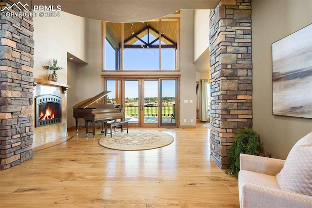 19155 Lochmere Ct, Monument, CO 80132 - living area with a stone fireplace, high vaulted ceiling, ornate columns, wood-type flooring, and baseboards