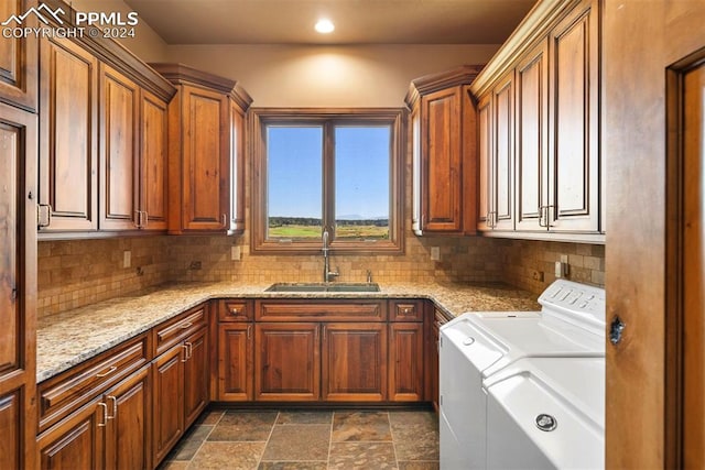 clothes washing area with cabinets, washer and dryer, and sink