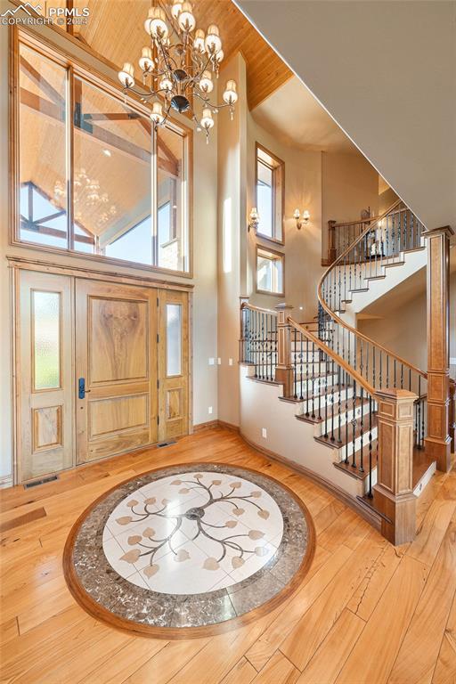 foyer with an inviting chandelier, hardwood / wood-style flooring, and a towering ceiling