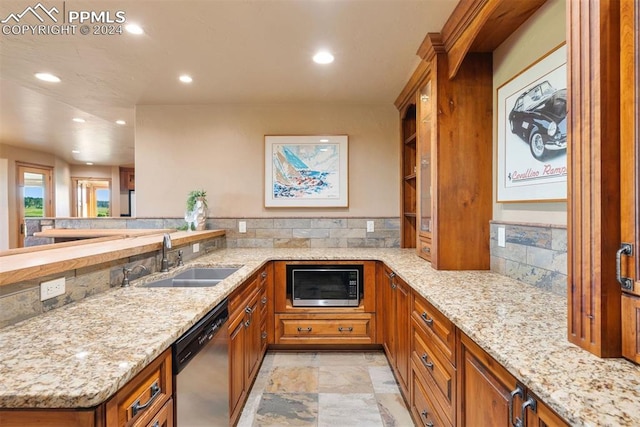 kitchen with appliances with stainless steel finishes, kitchen peninsula, sink, and light stone counters