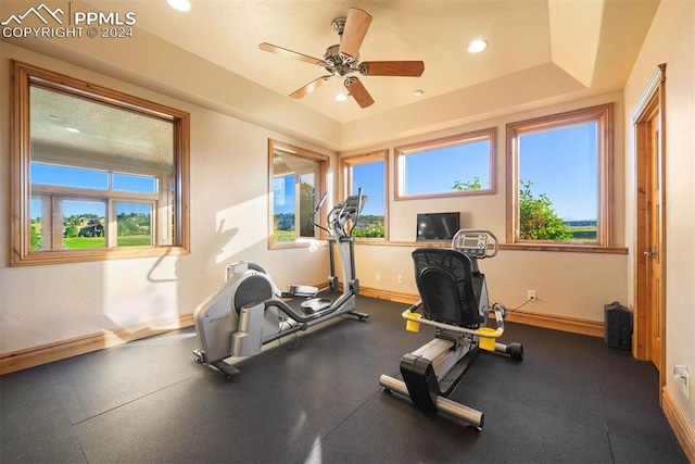 workout area with a wealth of natural light, a raised ceiling, and ceiling fan