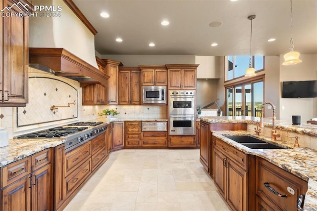 kitchen with appliances with stainless steel finishes, premium range hood, light stone countertops, pendant lighting, and sink