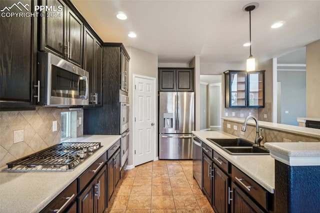 kitchen featuring dark brown cabinetry, hanging light fixtures, sink, appliances with stainless steel finishes, and decorative backsplash