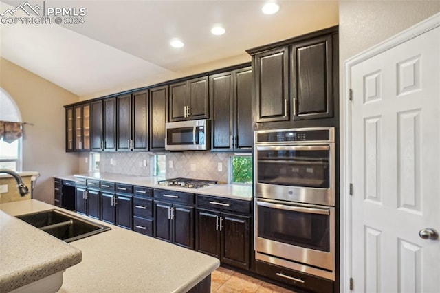 kitchen featuring backsplash, appliances with stainless steel finishes, light tile patterned flooring, and sink