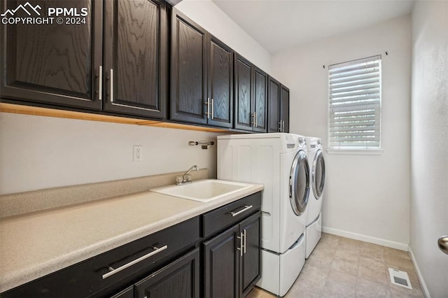 laundry area with cabinets, washing machine and dryer, light tile patterned floors, and sink