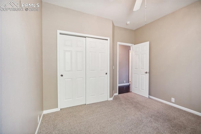 unfurnished bedroom with ceiling fan, a closet, and light carpet