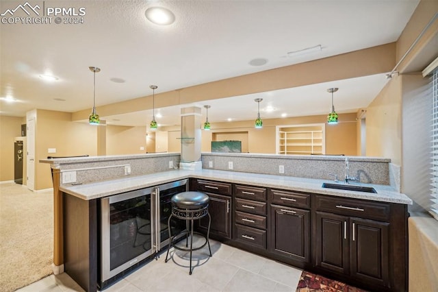 kitchen with dark brown cabinetry, pendant lighting, wine cooler, and sink