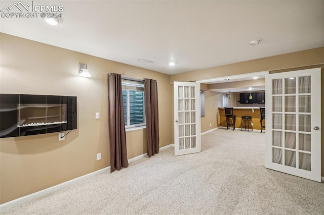 carpeted spare room with french doors and indoor bar