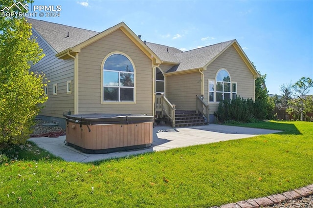 back of property with a lawn, a patio, and a hot tub