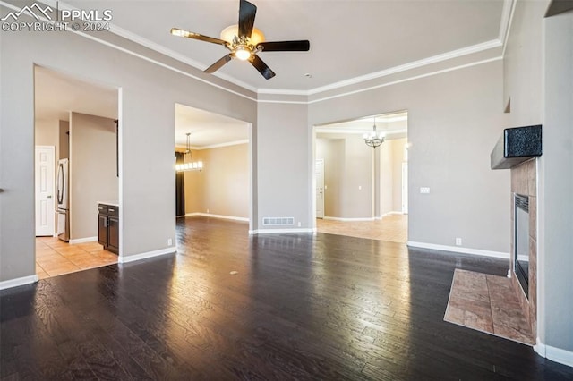 unfurnished living room featuring light wood-type flooring, ceiling fan with notable chandelier, ornamental molding, and a tile fireplace